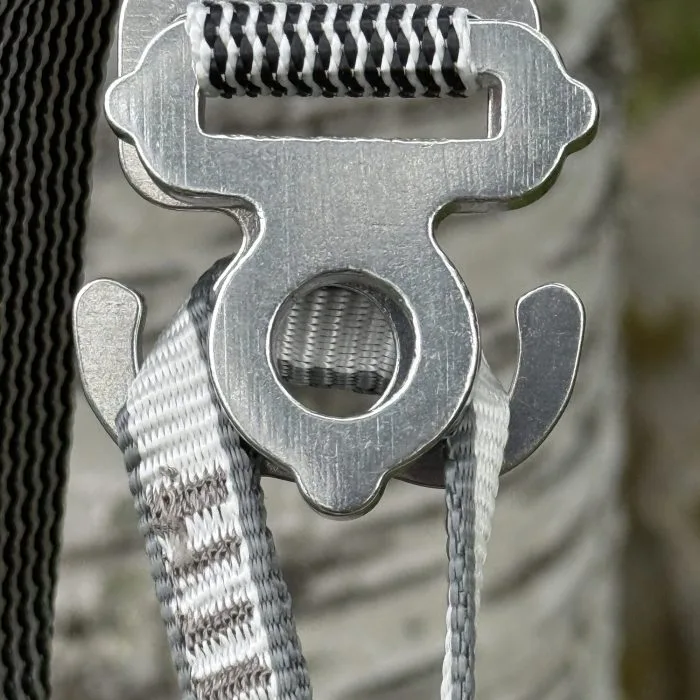 Jord Buckle i borstad aluminium, spännet format som Momo Jord-loggans J och O, mot björkstam