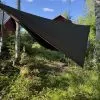 Momo Jord asymmetrisk tarp för äldre hammock uppspänd mellan björkar med blå himmel och röd stuga