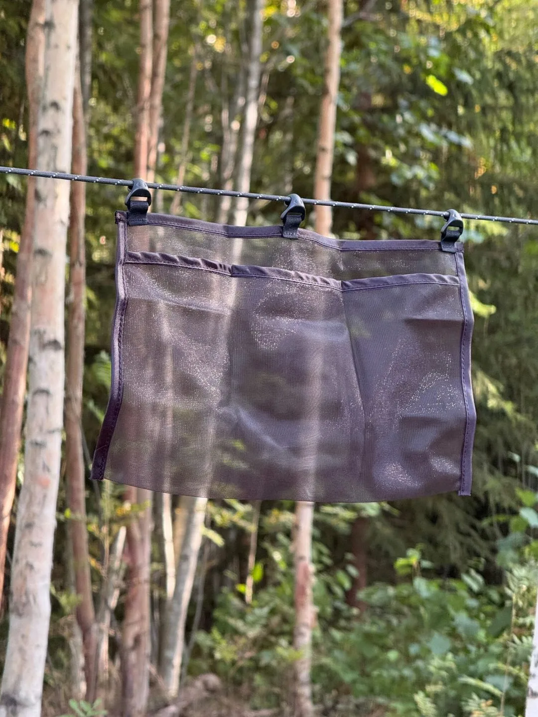 Hammockficka i myggnätsmesh upphängd i en lina mellan träd