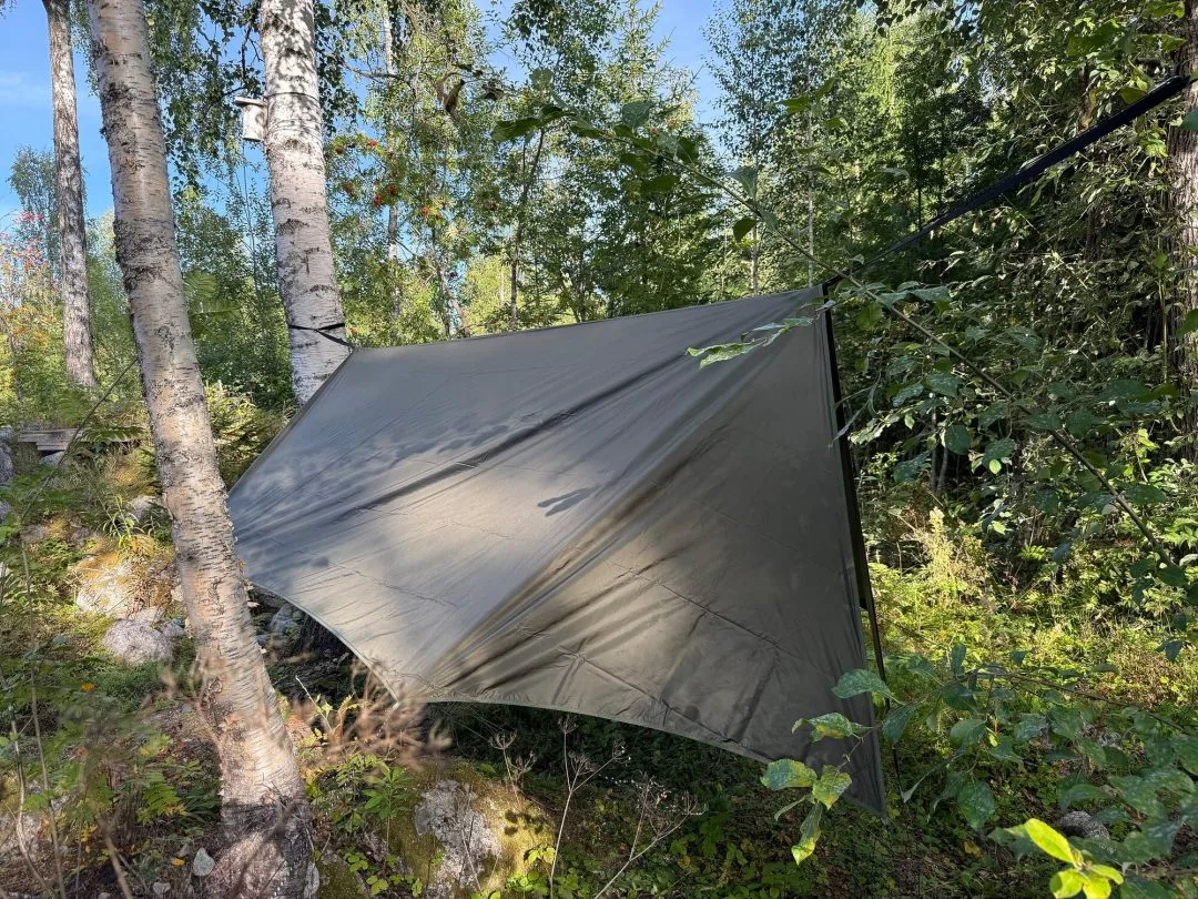 Vintertarp spänd som regnskydd över en hängmatta i skogen